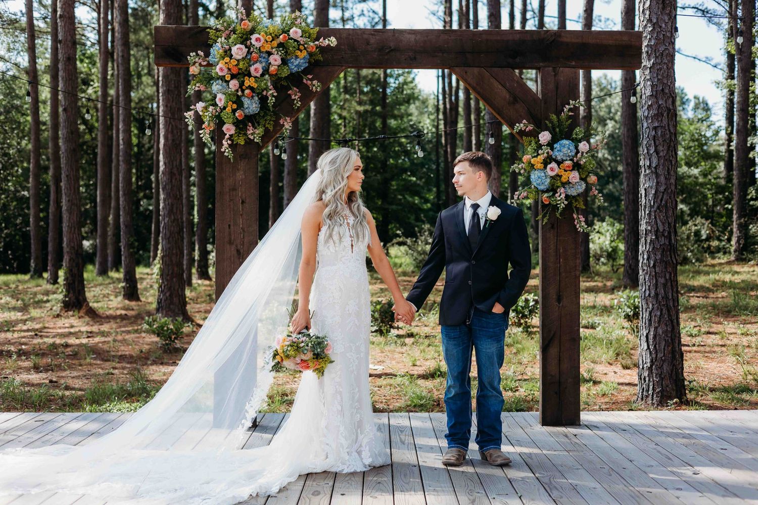Panoramic view of wedding ceremony site with wooden arch and pine forest backdrop.