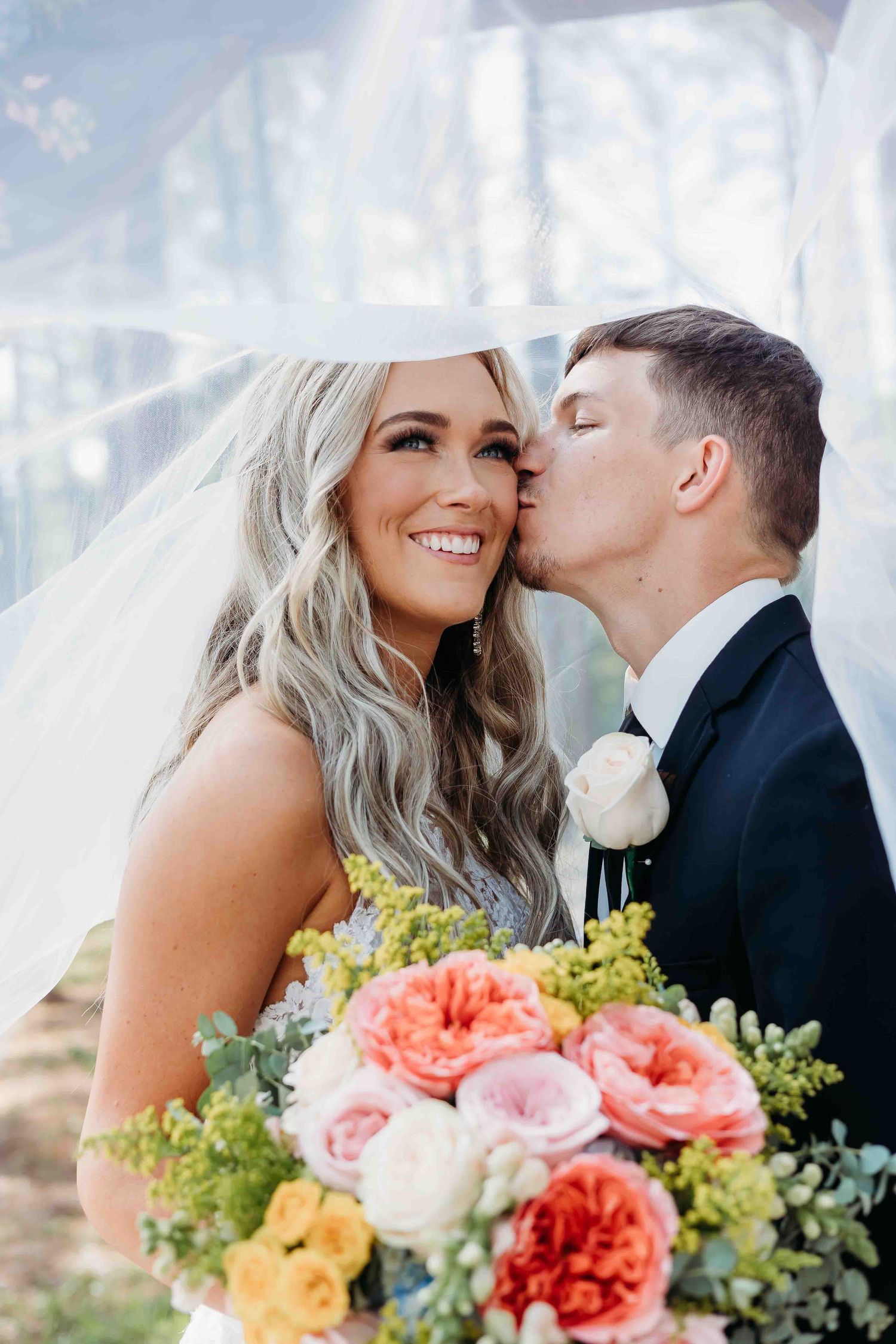 Tender wedding moments captured with vibrant floral bouquet and soft white background.