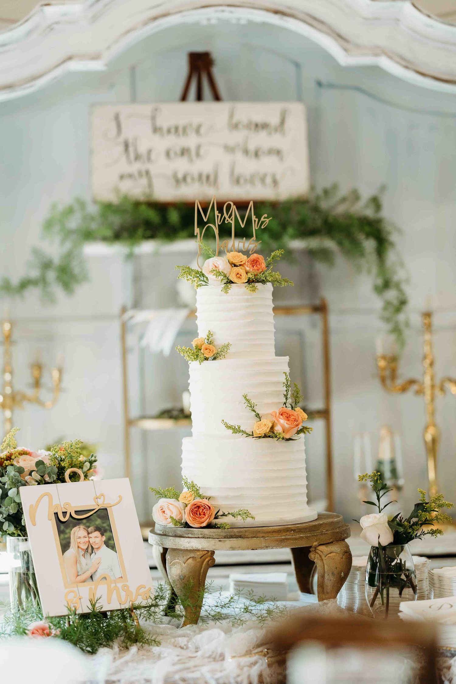 Elegant white wedding cakes decorated with fresh flowers displayed on wooden stands.