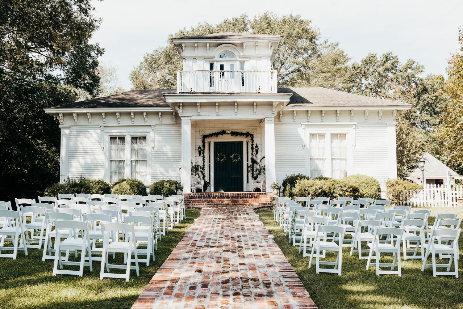 An elegant white wedding venue with colonial architecture and outdoor ceremony setup.