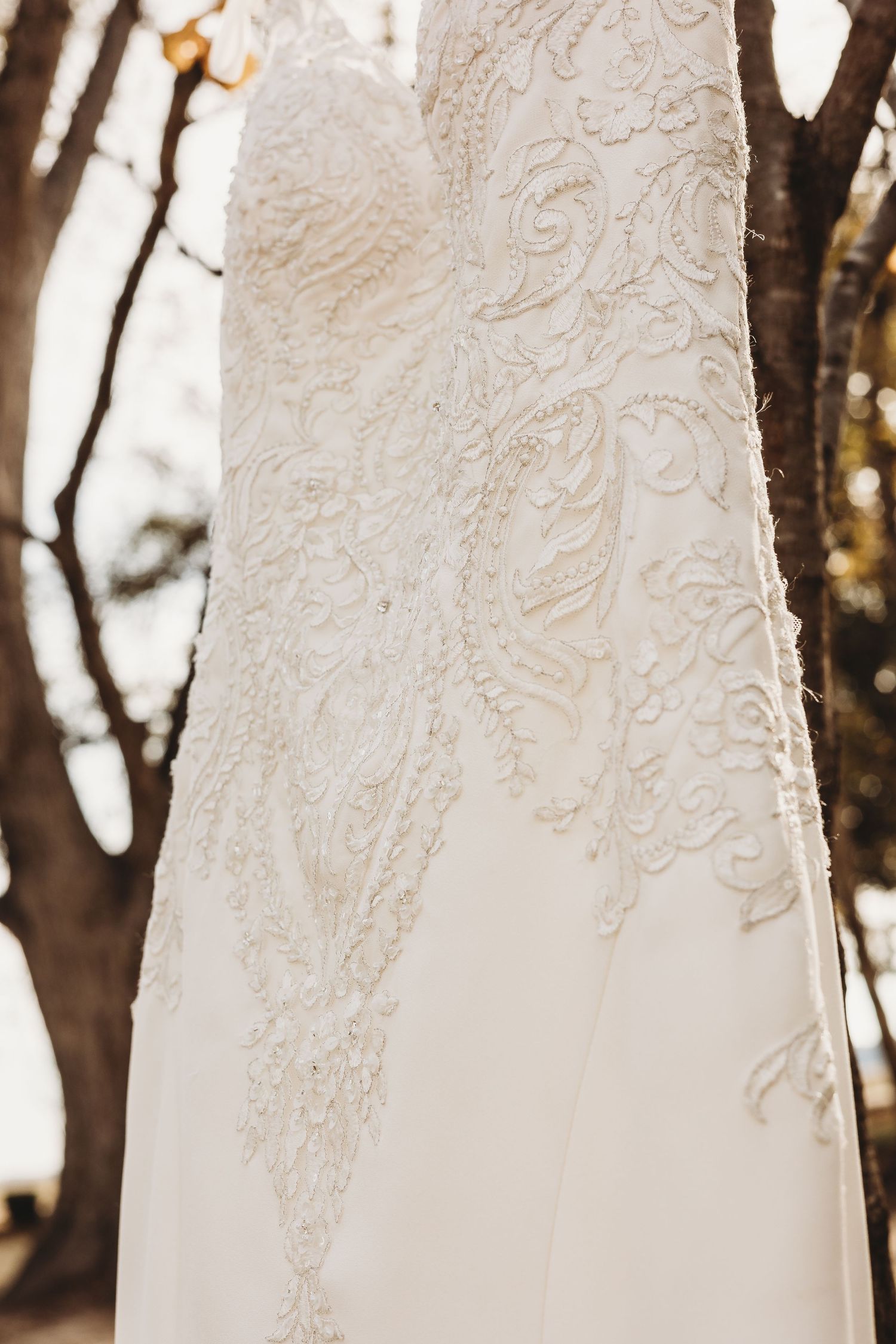 Close-up of delicate beadwork and embroidery on an elegant white wedding gown.