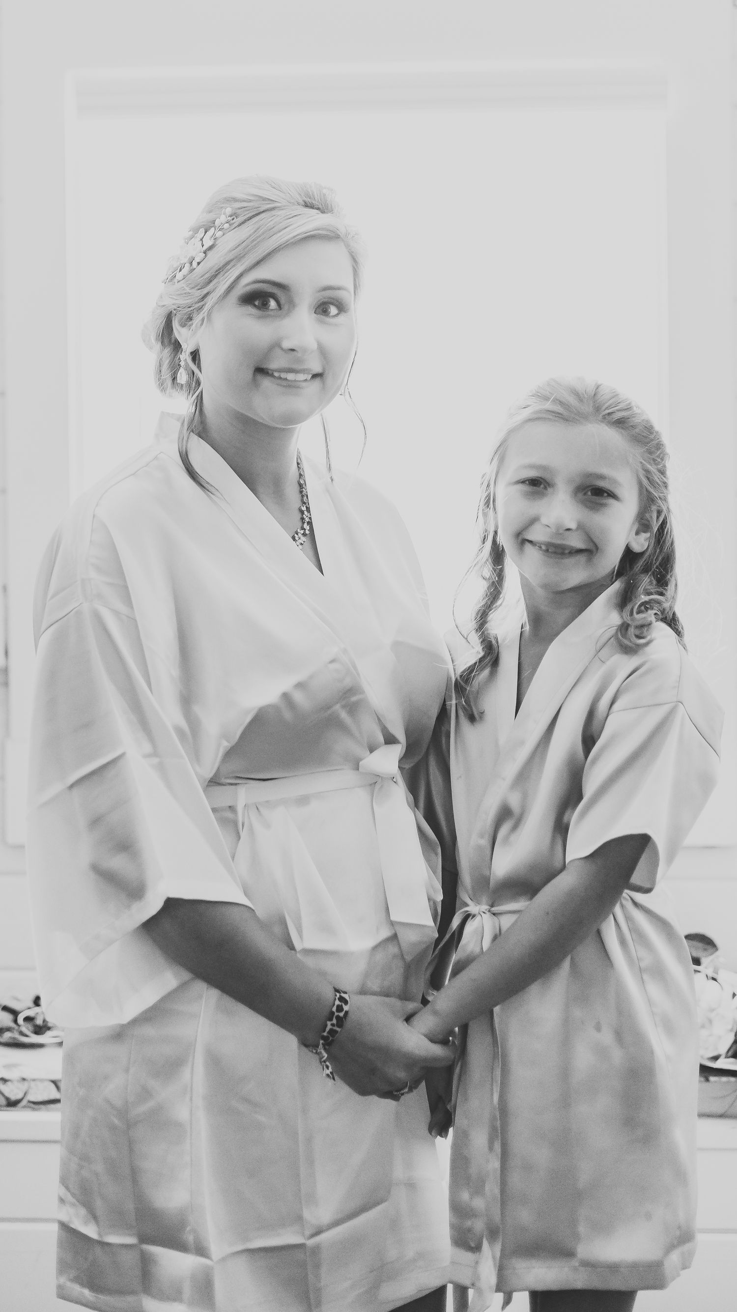 Black and white candid photo of wedding morning preparations in matching robes.