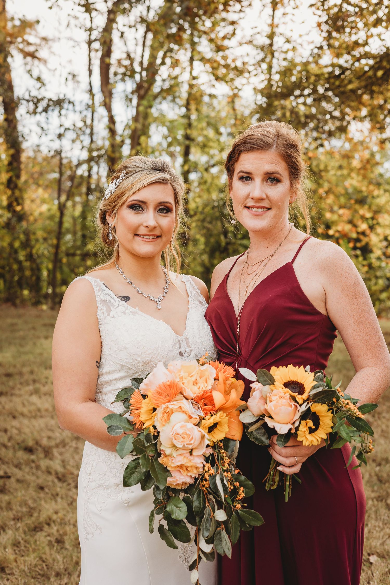 Wedding party poses with peach and sunflower bouquets against golden autumn backdrop.