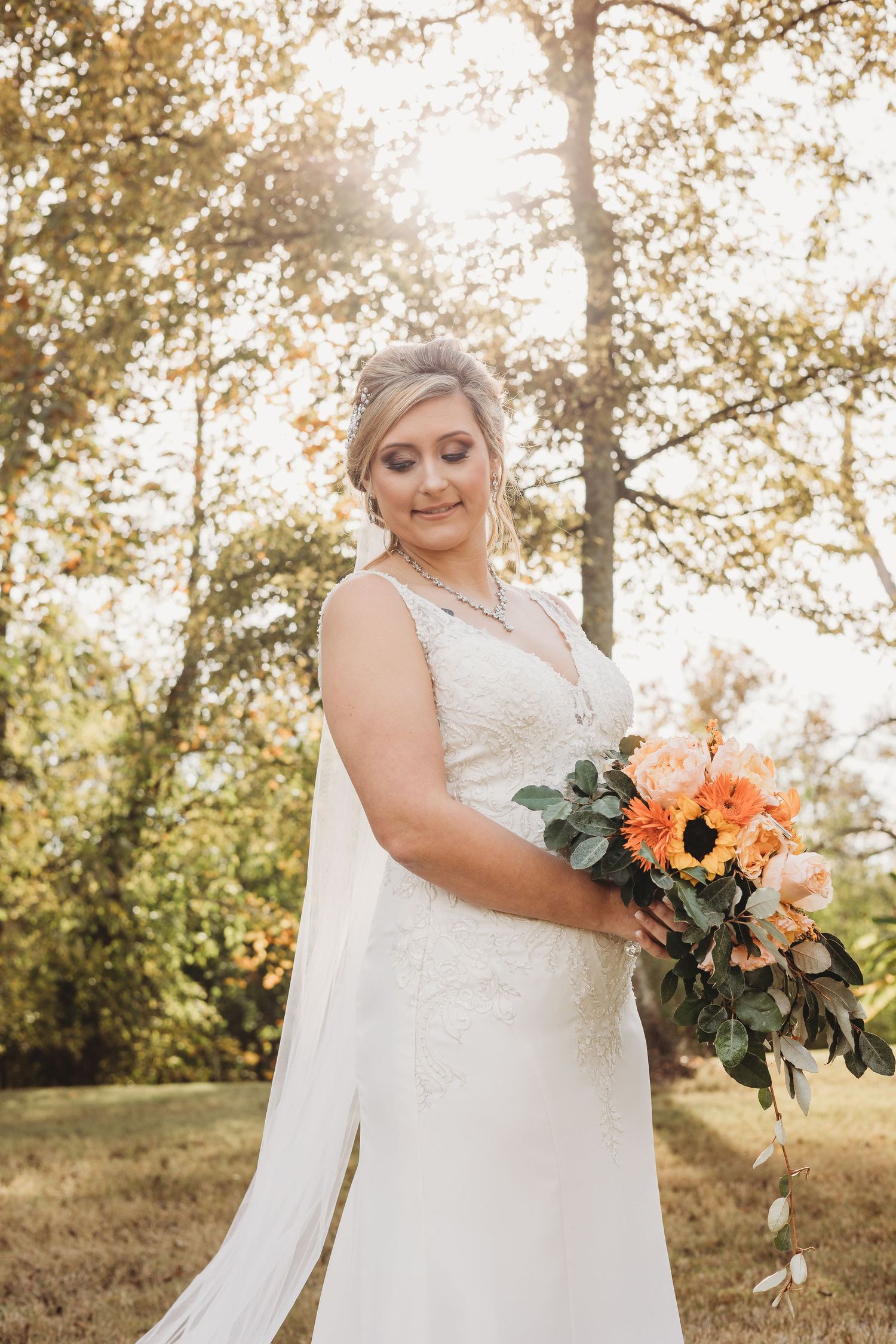 Elegant wedding photography showing flowing white dress and autumn florals in golden sunlight.