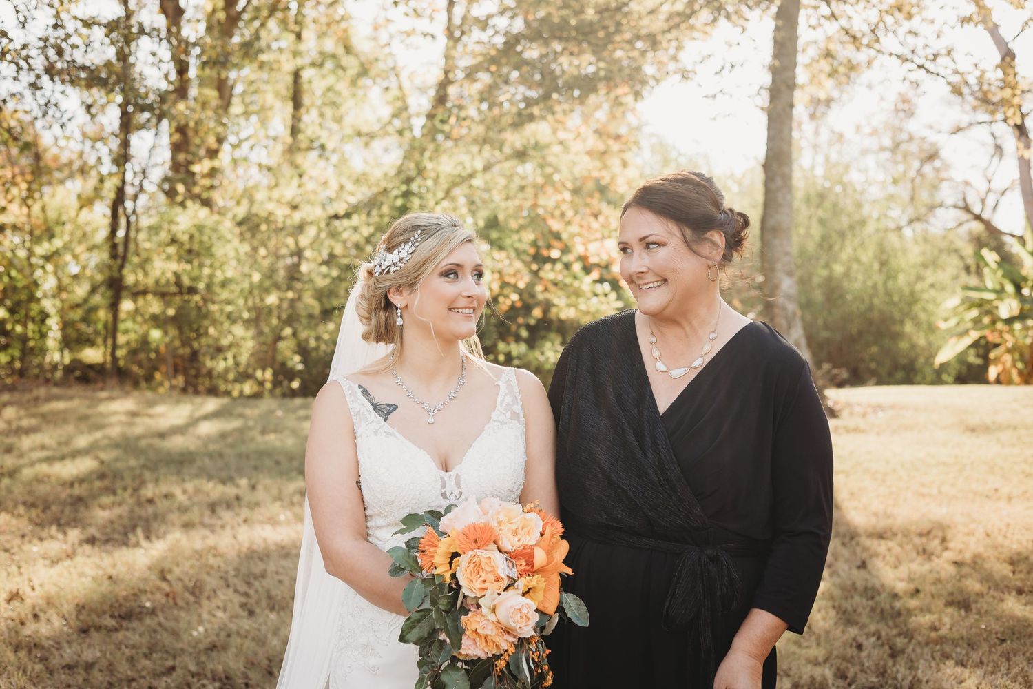 Wedding party poses in outdoor setting with warm evening light filtering through trees.