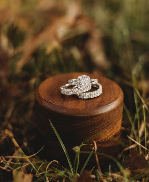Wedding rings displayed on wooden surface in natural outdoor lighting.