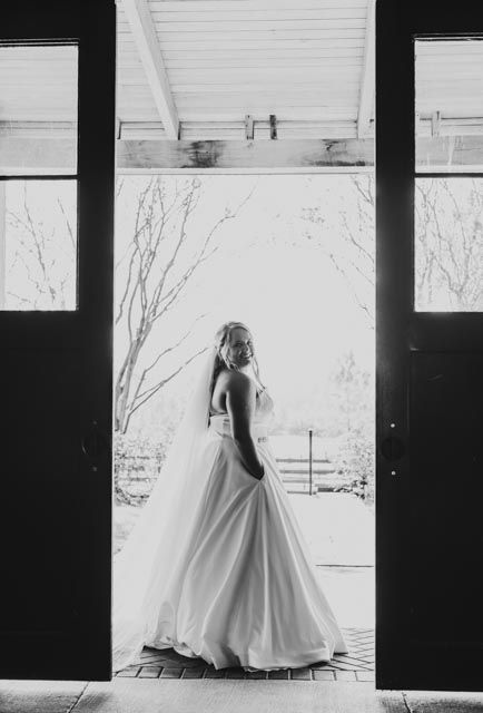 Silhouette of bride in flowing gown against white backdrop in black and white.