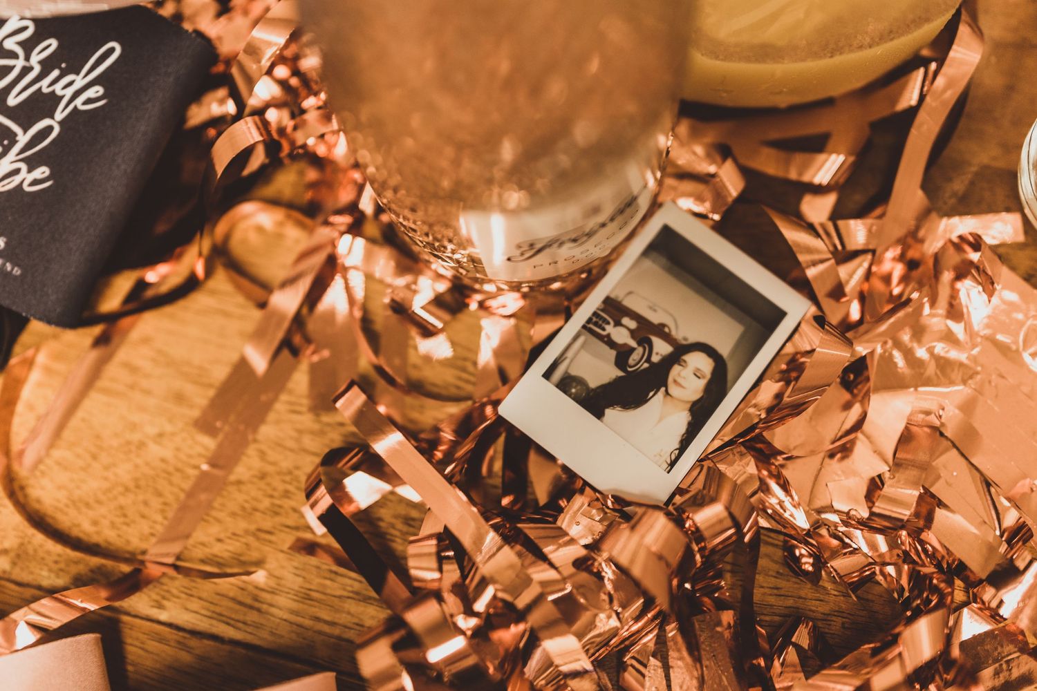 Decorative rose gold party elements and metallic accents arranged on a wooden surface.