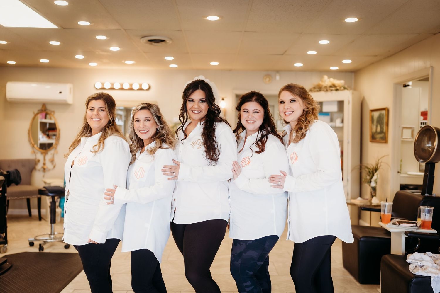 A group wearing coordinated white button-down shirts and dark pants posing together indoors.