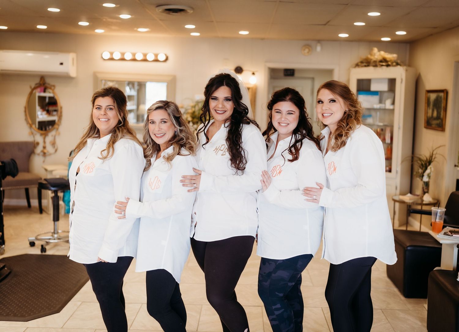 Friends in matching white tops and navy bottoms pose together in a bright indoor space.