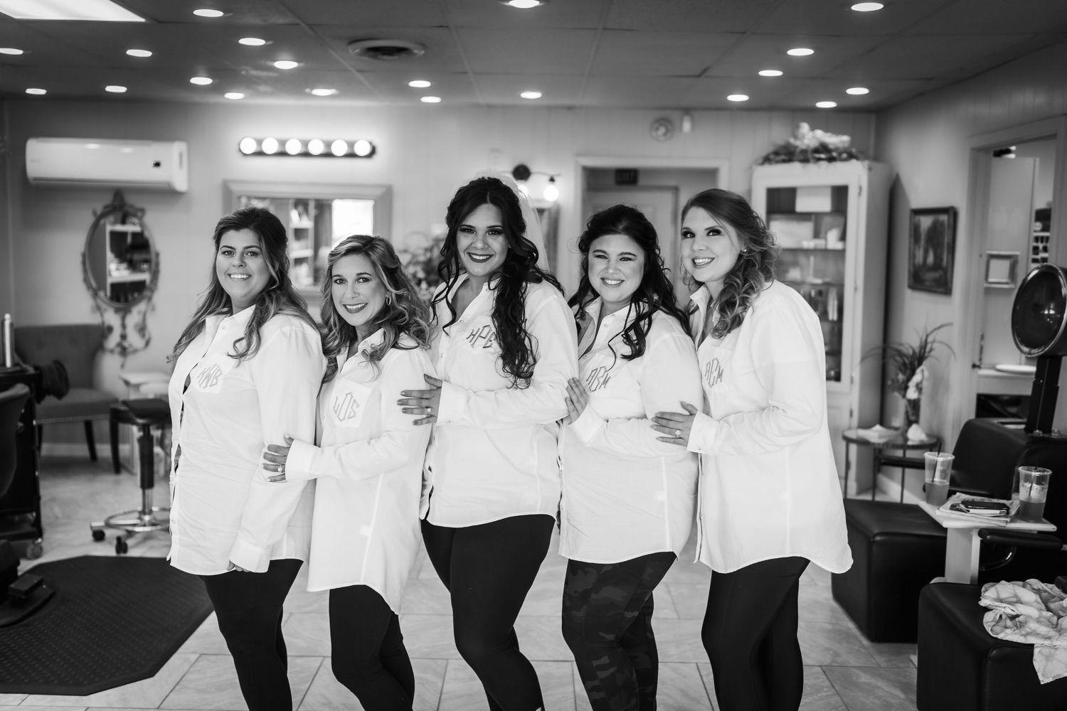 Group photo of people in coordinated white shirts and dark pants under recessed lighting.