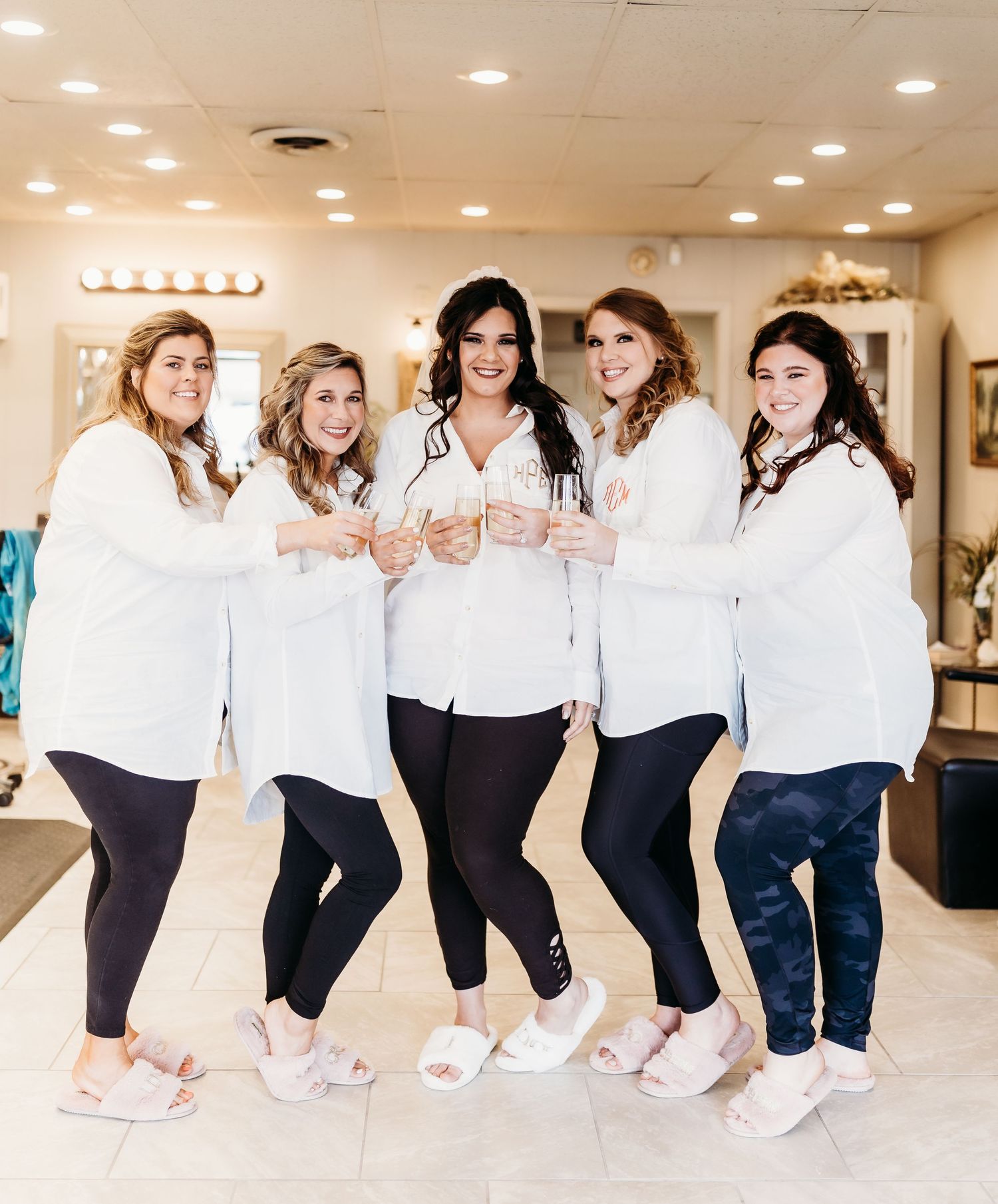 Friends in matching white shirts and dark pants strike various poses in a bright indoor space.