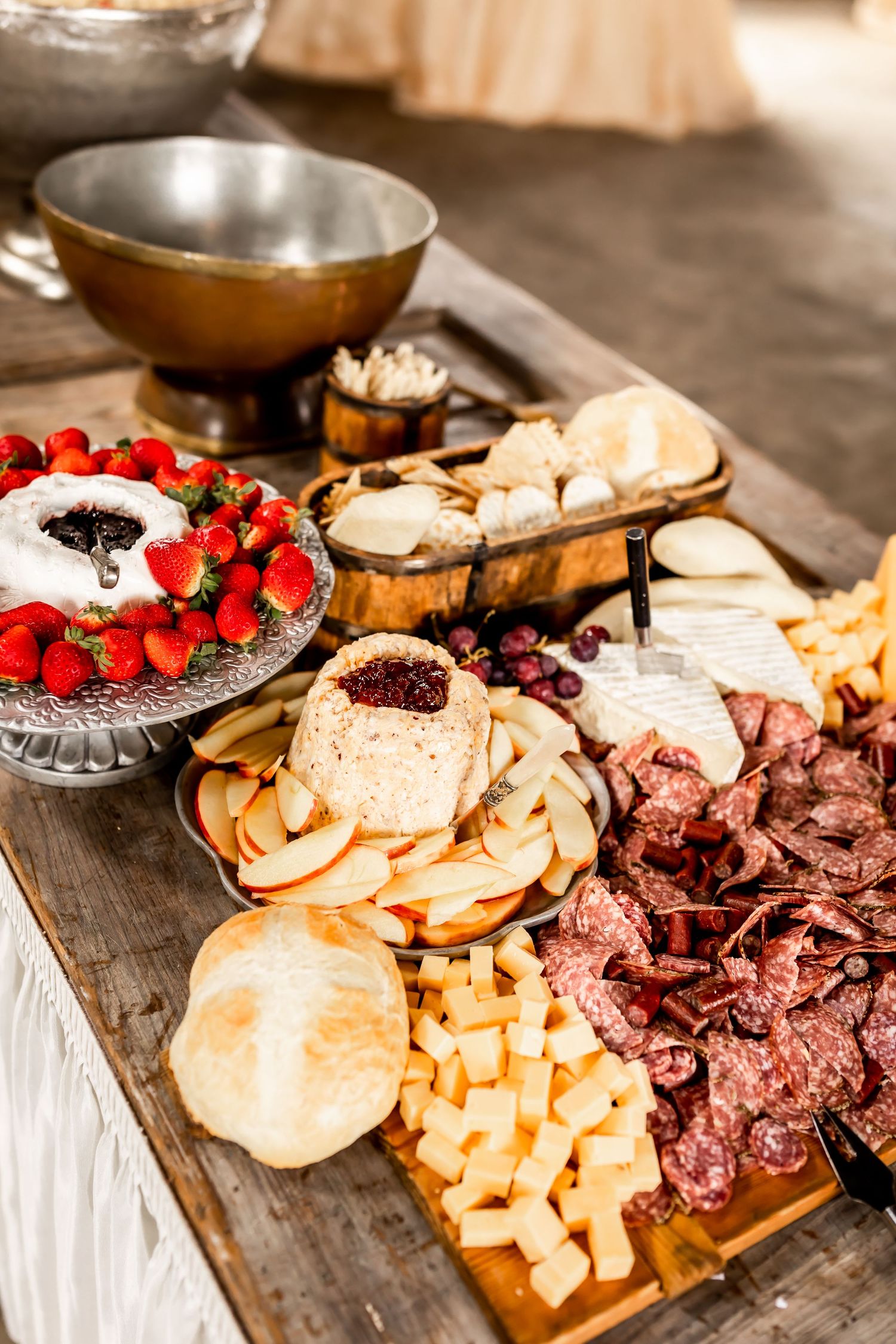 Charcuterie board with meats, cheeses, crackers, and fresh berries arranged on white linens.