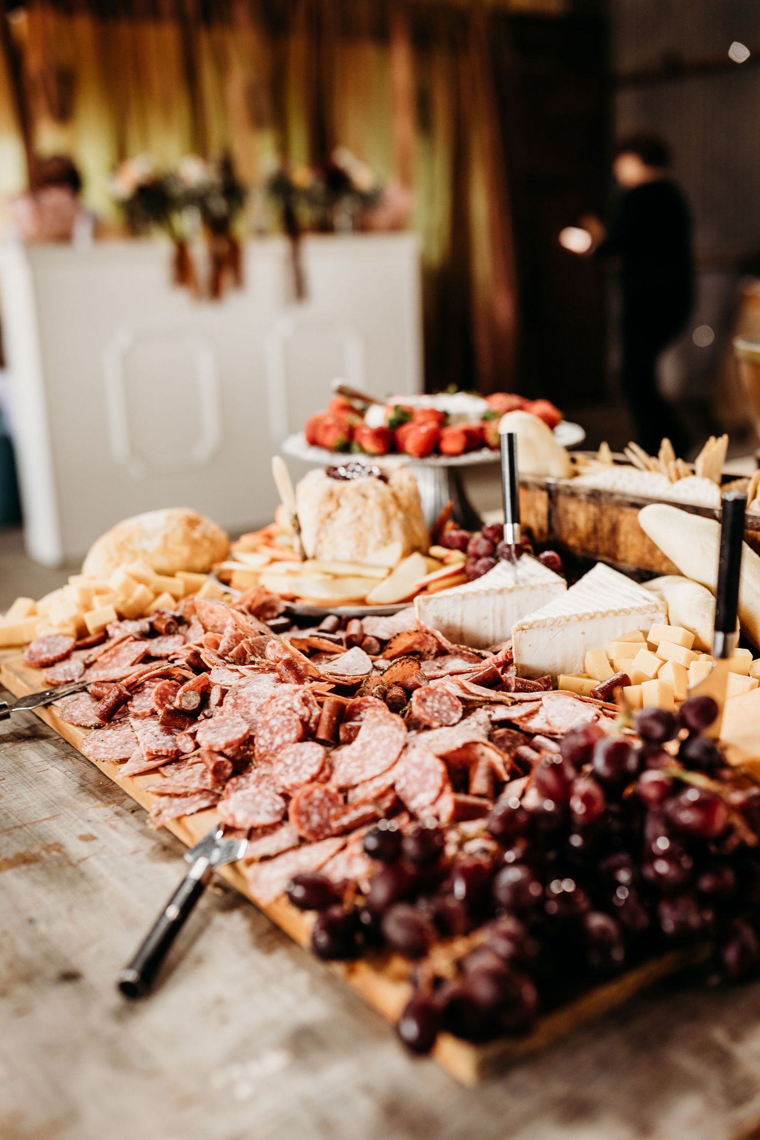 Rustic charcuterie board display with meats, cheeses and grapes arranged on wooden surface at wedding reception.