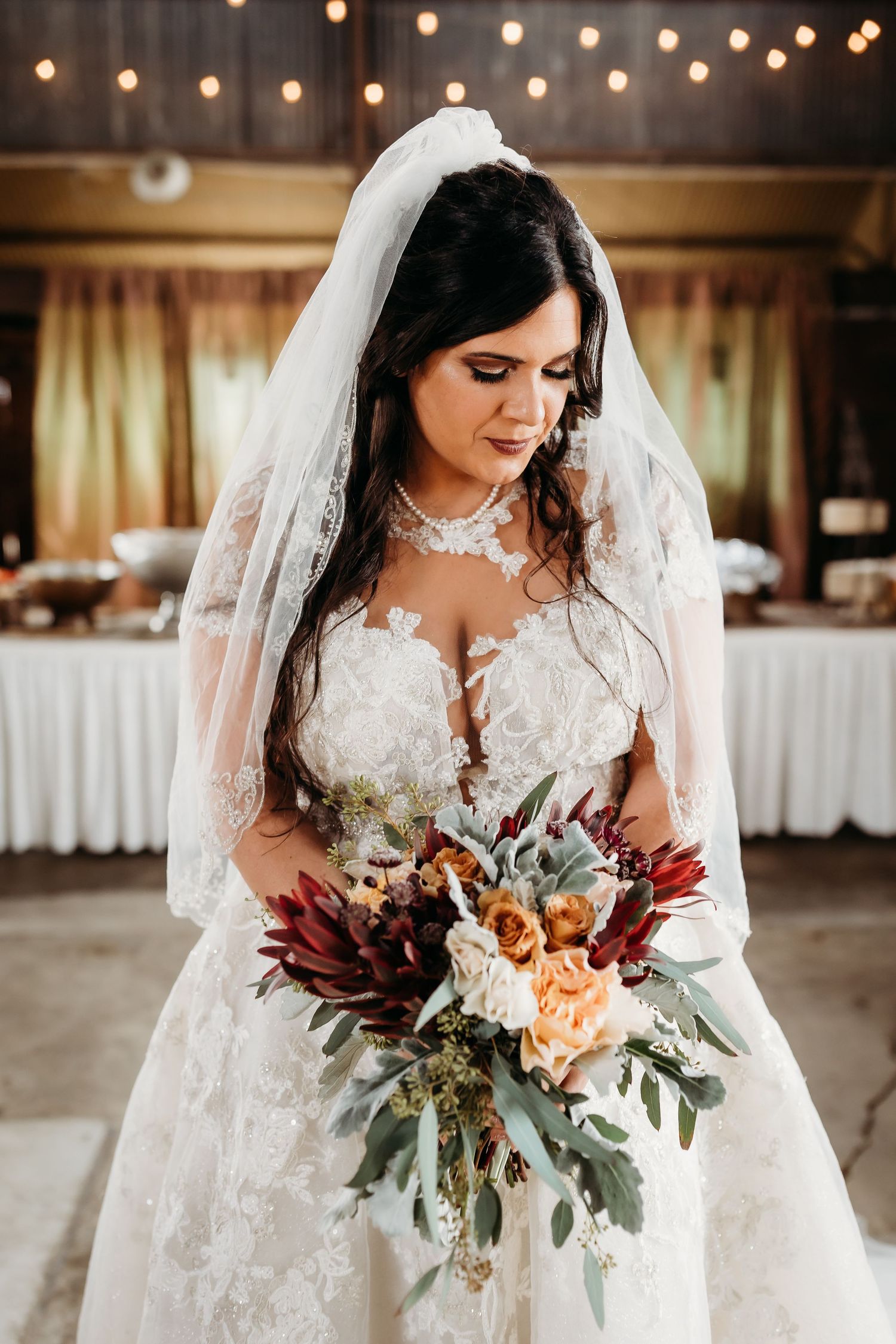Close-up bridal portrait showcasing detailed lace dress and autumn-colored bouquet.