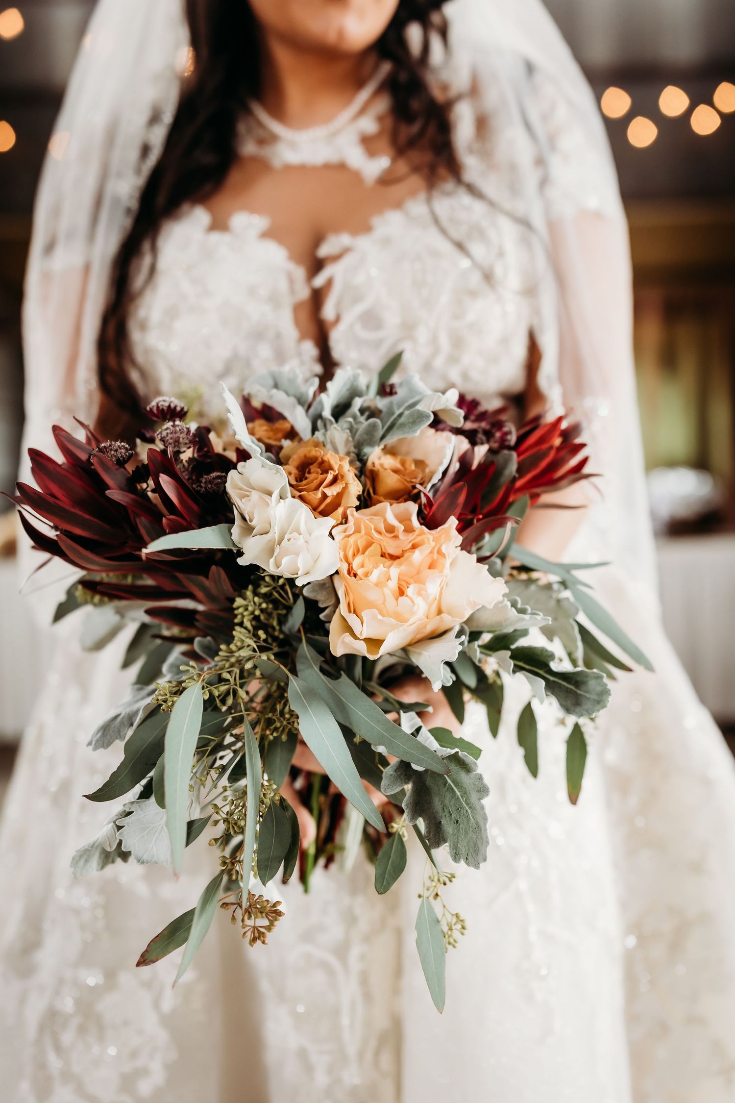 Close-up of bridal bouquet with burgundy dahlias, peach roses and eucalyptus.