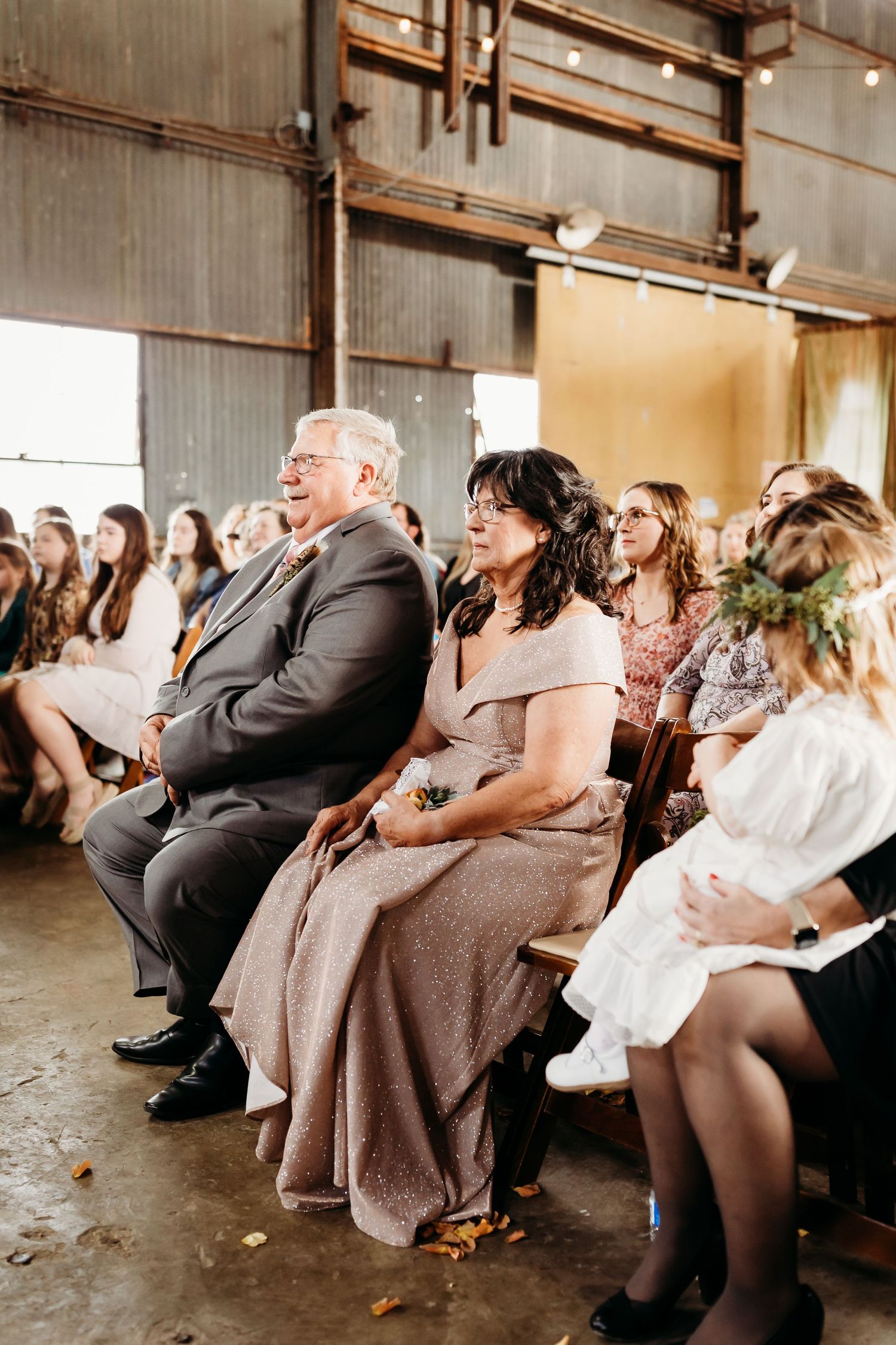 Wedding guests seated in rows watch the ceremony in an industrial warehouse venue.