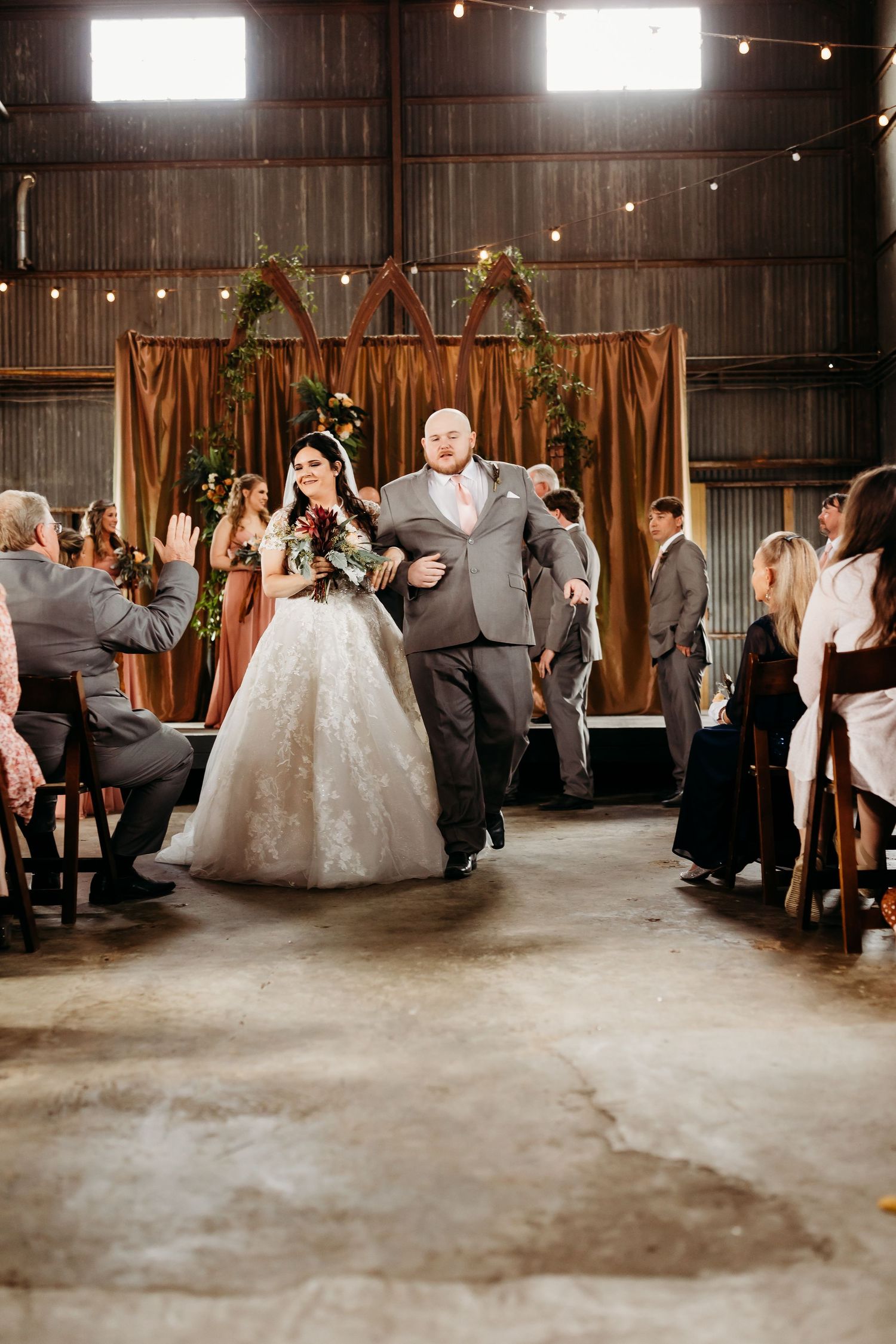 Wedding guests cheer and celebrate during a joyful moment at rustic indoor reception.