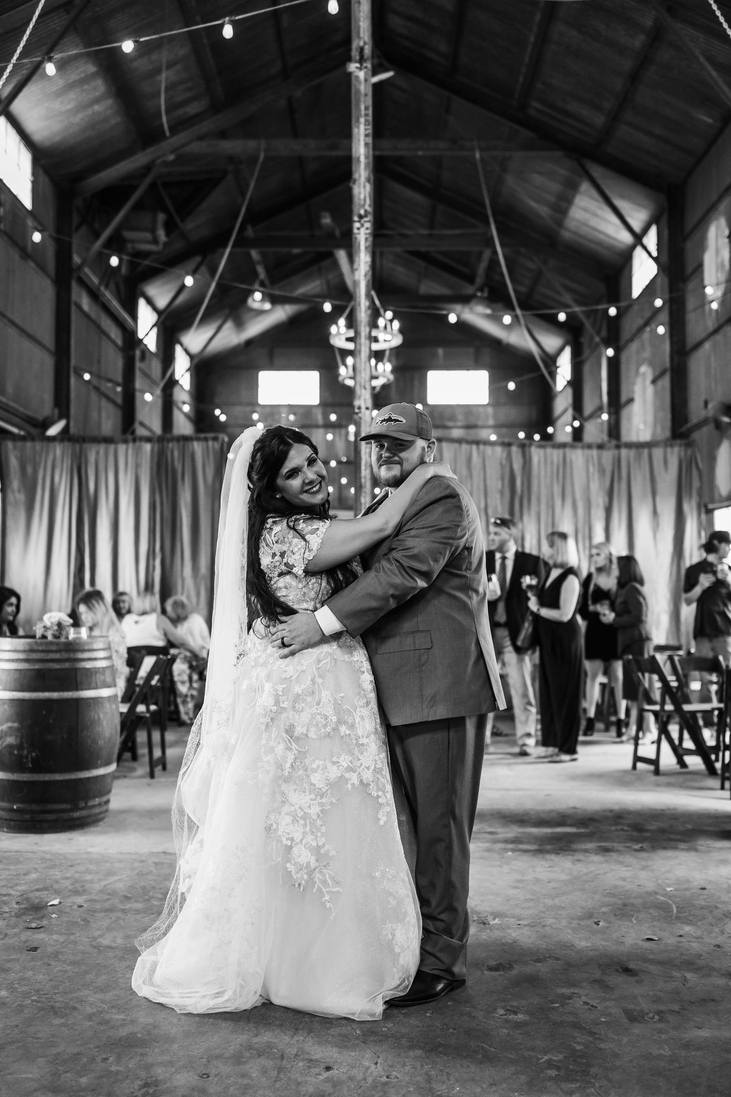 A monochrome capture of a romantic dance in a barn wedding venue with rustic decor.