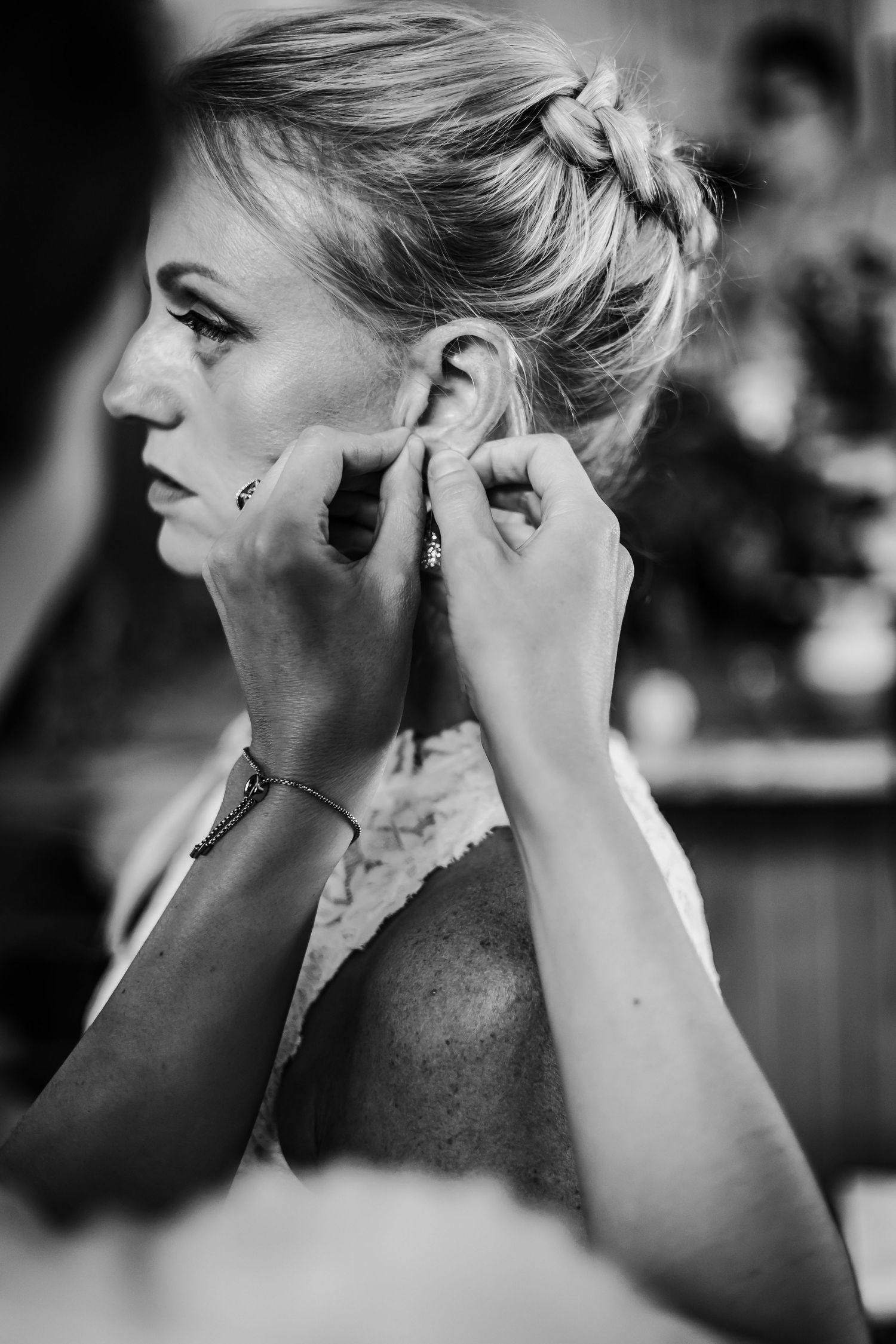 Side profile view of someone putting on earrings in black and white.