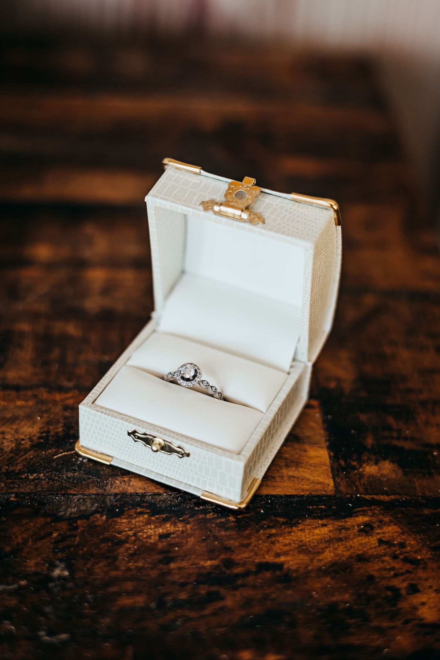 Wedding rings displayed in white jewelry boxes on rustic wooden surface.