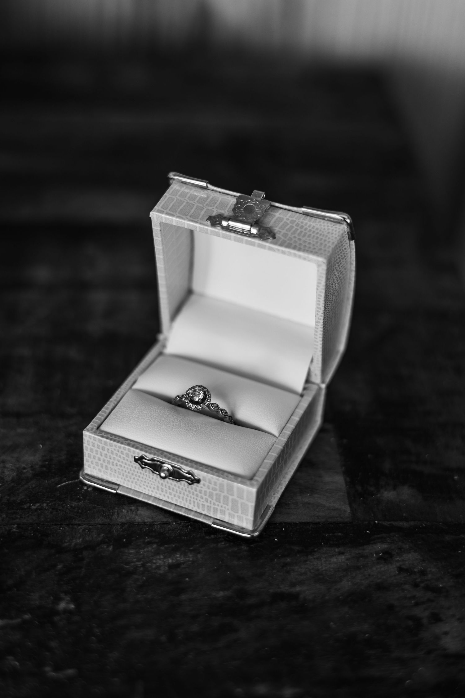 Black and white photo of engagement rings in white jewelry boxes.
