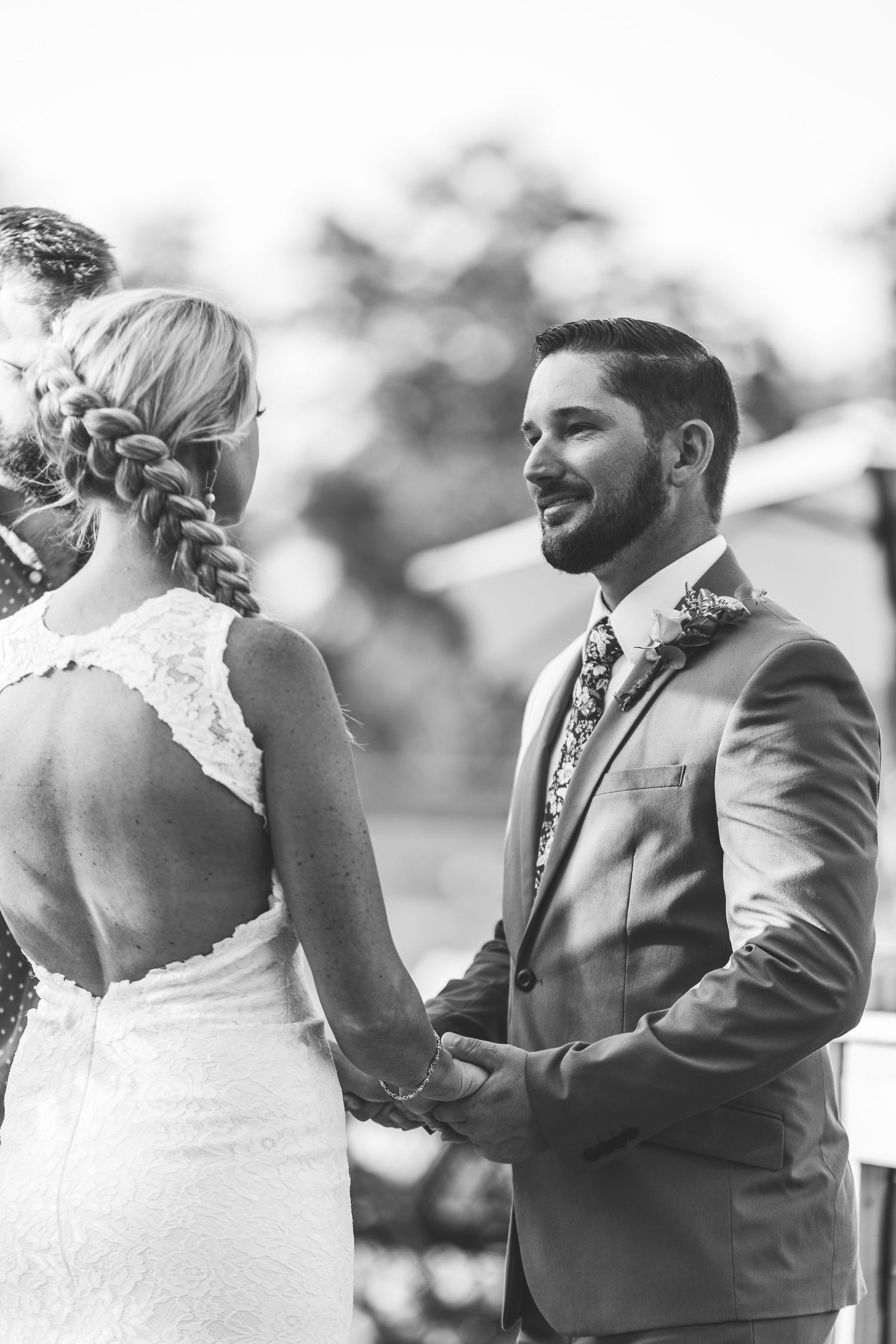 A tender moment during an outdoor wedding ceremony as the couple holds hands.