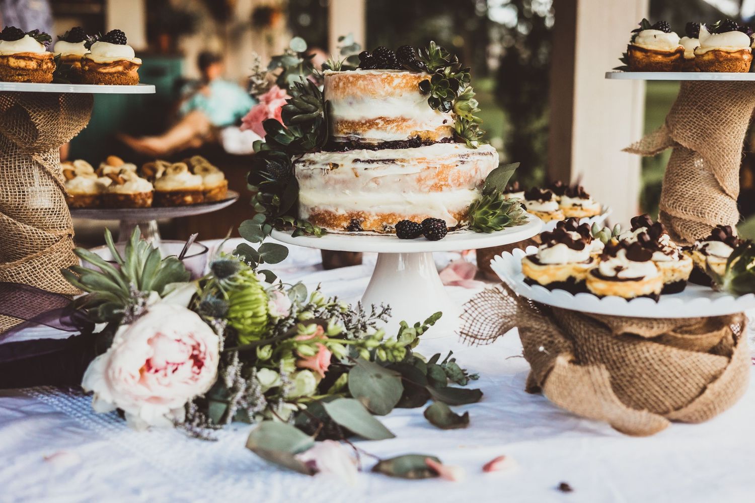 Elegant dessert table featuring a naked cake and cupcakes decorated with fresh florals.