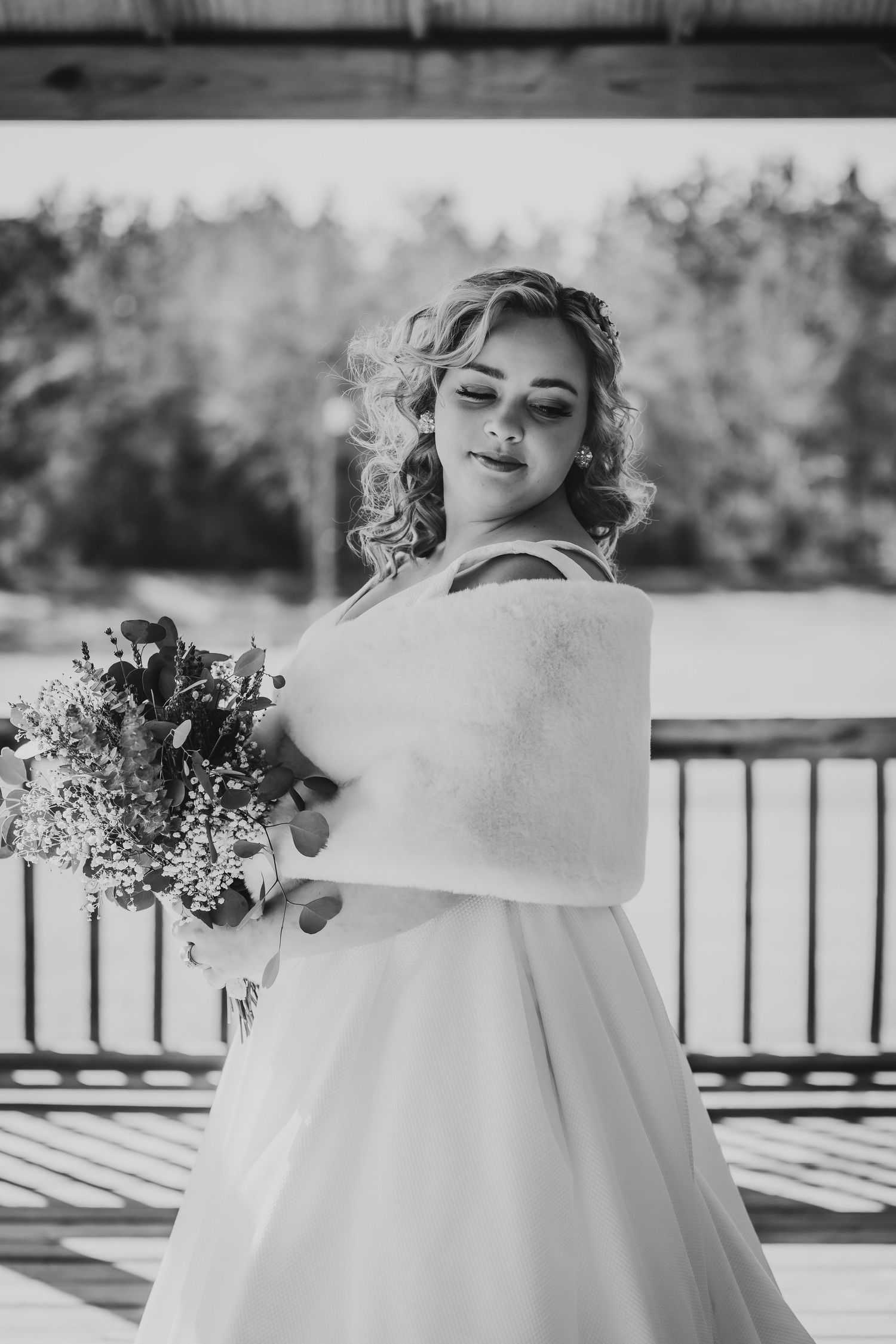 Black and white bridal photo showing classic wedding dress with white wrap and floral bouquet.
