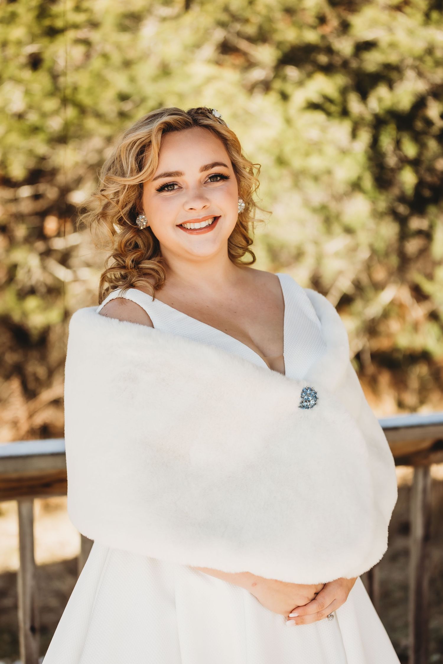 Elegant bridal portrait in warm sunlight featuring white wrap and classic wedding dress.