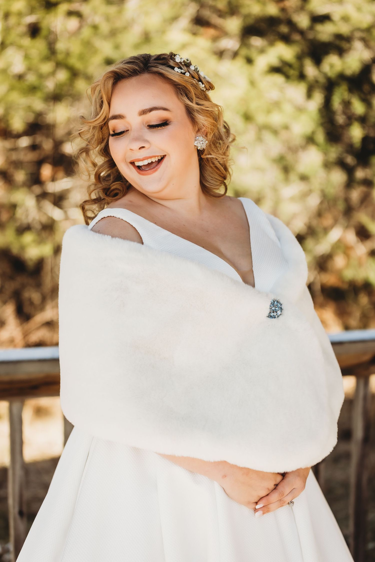 Romantic bridal portrait with floral crown and white wrap against natural background.