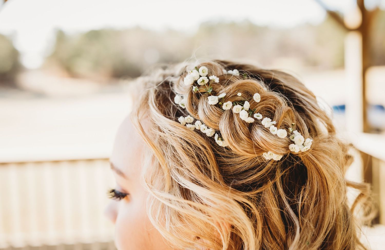 Close-up detail of a delicate bridal hairstyle adorned with small white flowers and pearls.