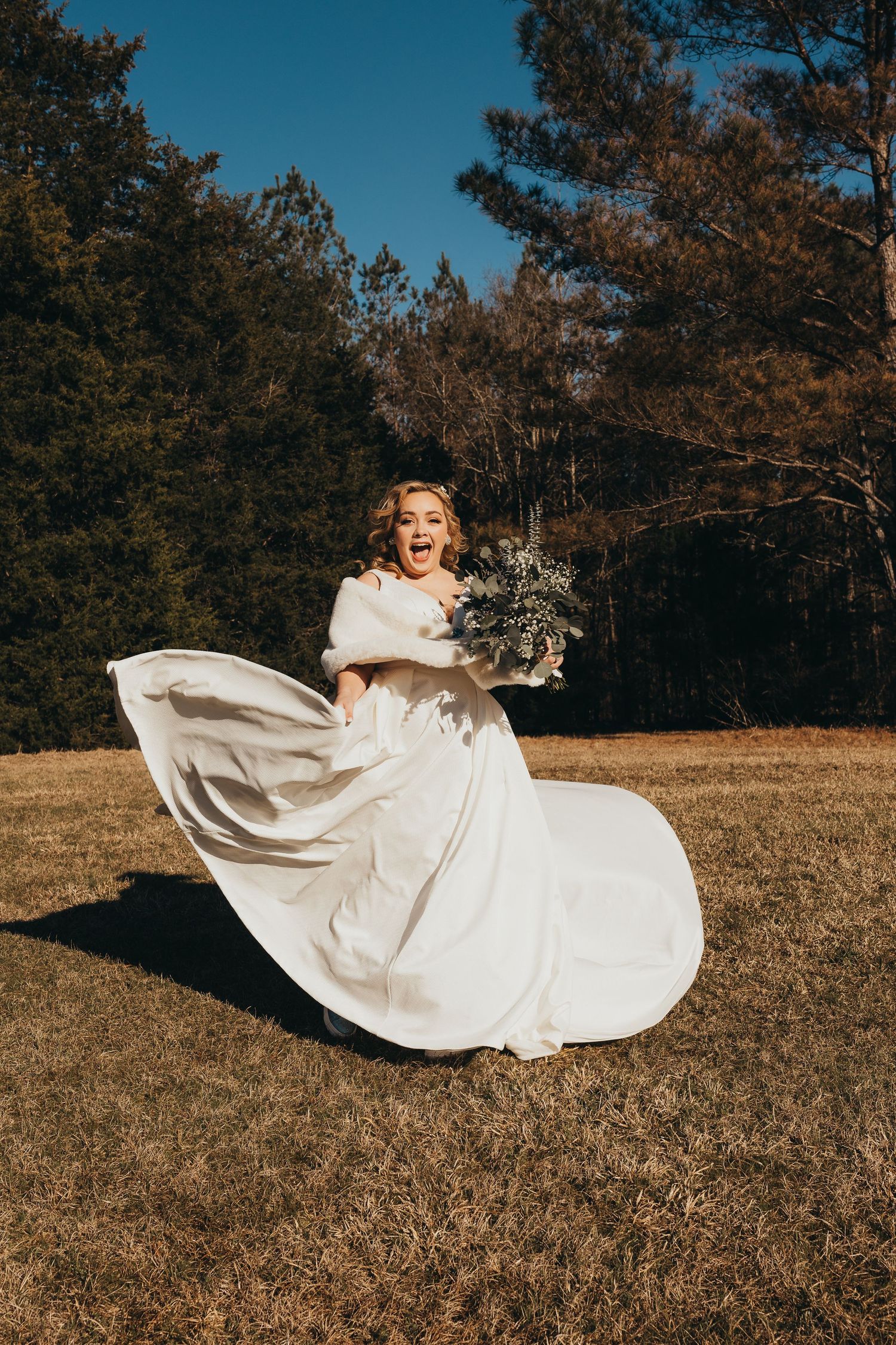 Joyful bridal portrait in a flowing white dress spinning in an autumn field.