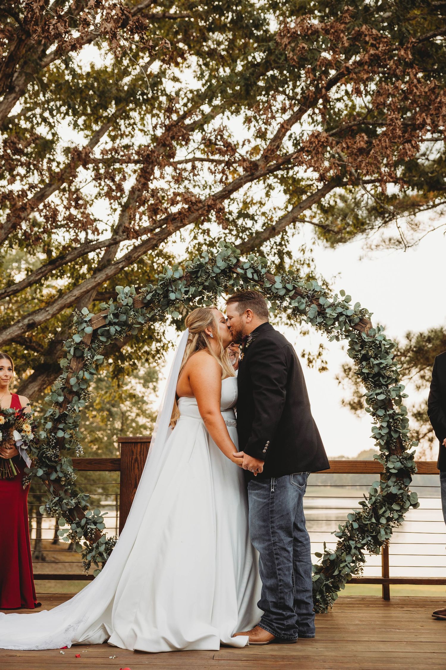 Wedding ceremony moment under a floral arch with greenery and white decorations.