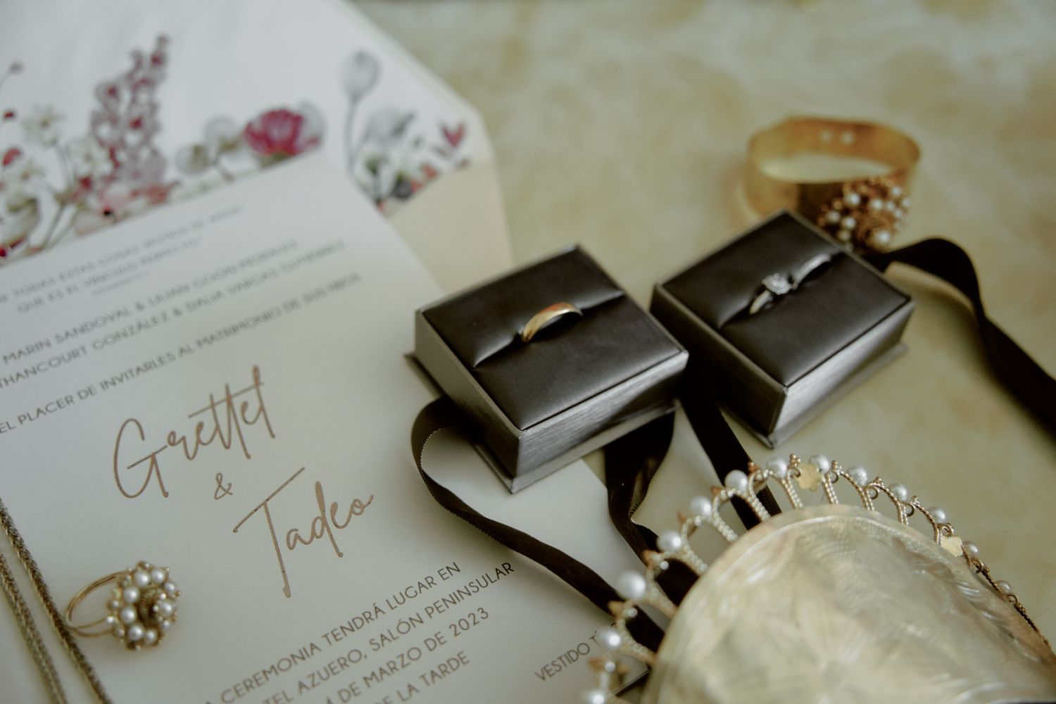 Wedding invitation and jewelry boxes arranged with floral designs.