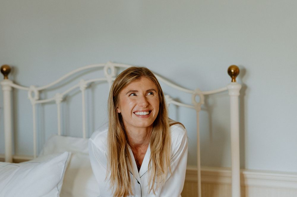 A morning scene shows a person in white pajamas sitting on a bed with brass headboard.