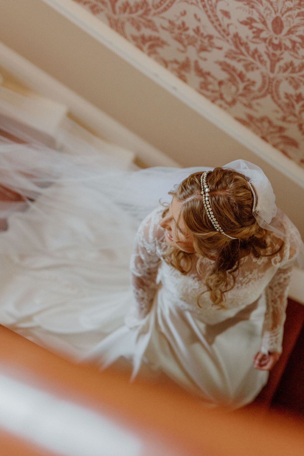 Overhead view of a bride in a white lace wedding dress with a crystal headpiece and flowing veil.