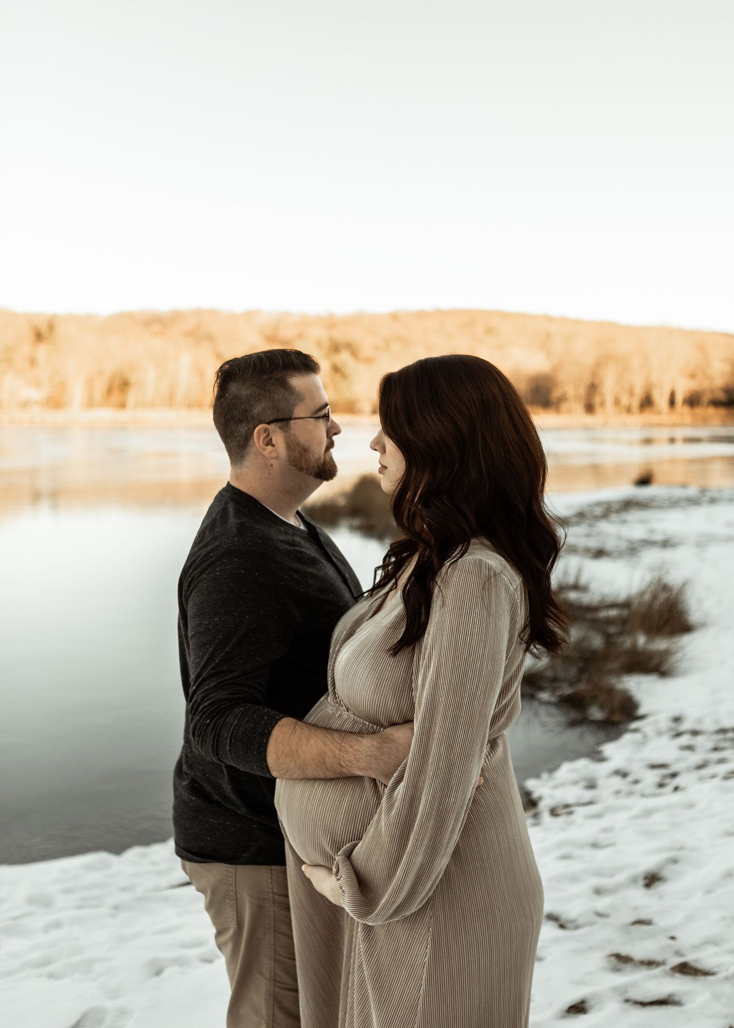A tender winter lakeside moment between a couple at sunset.