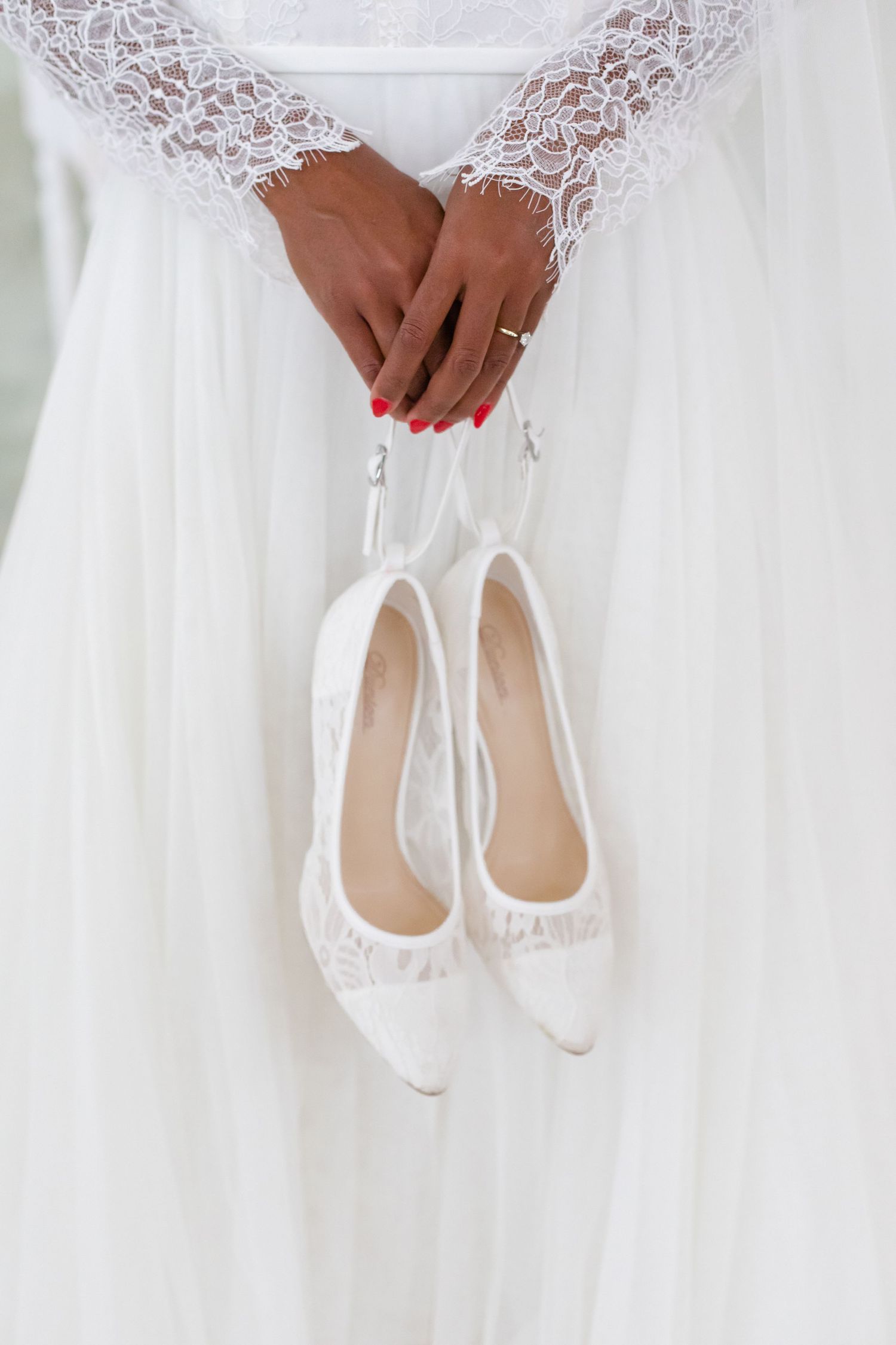 White lace wedding dress detail with matching bridal flats.