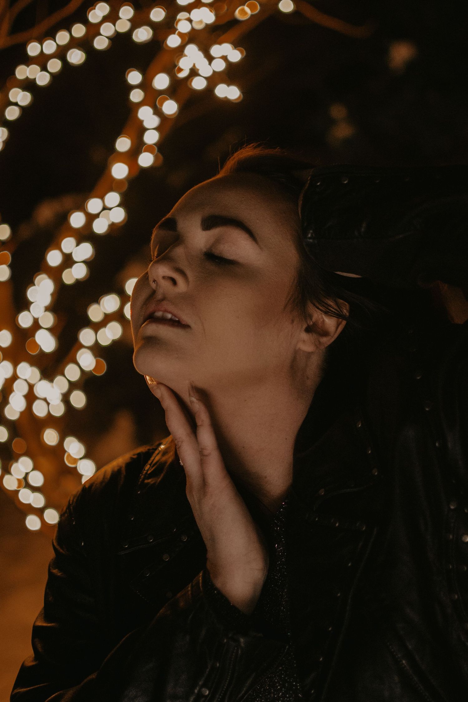 Dramatic nighttime portrait with bokeh lights creating a dreamy effect in the background.