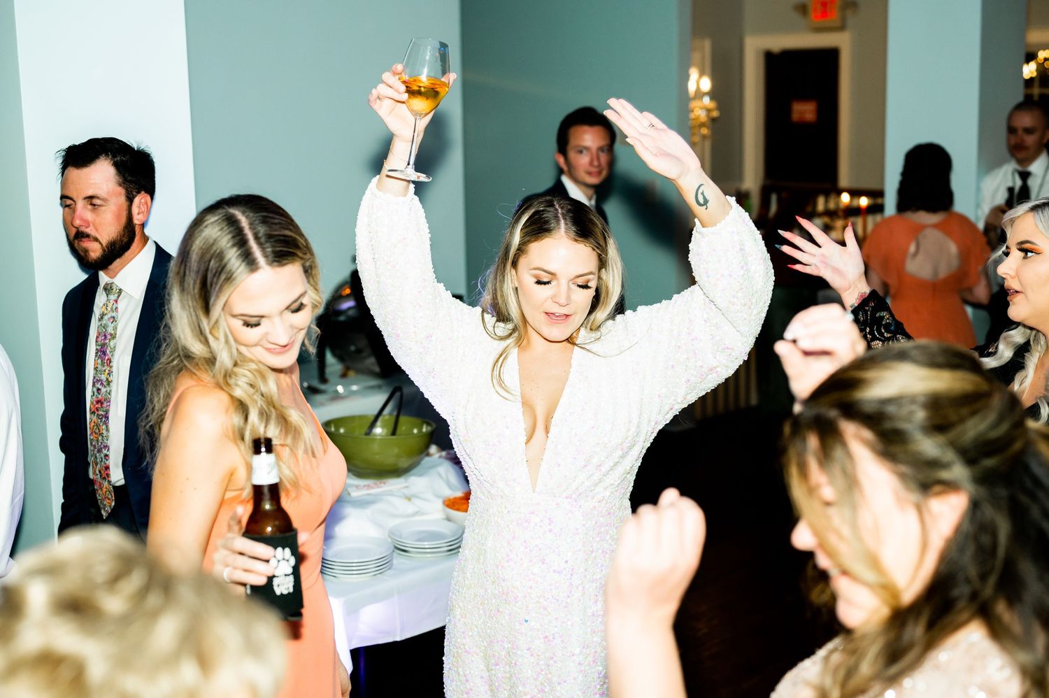 Lively wedding reception with guests dancing and having fun in a bright indoor venue.