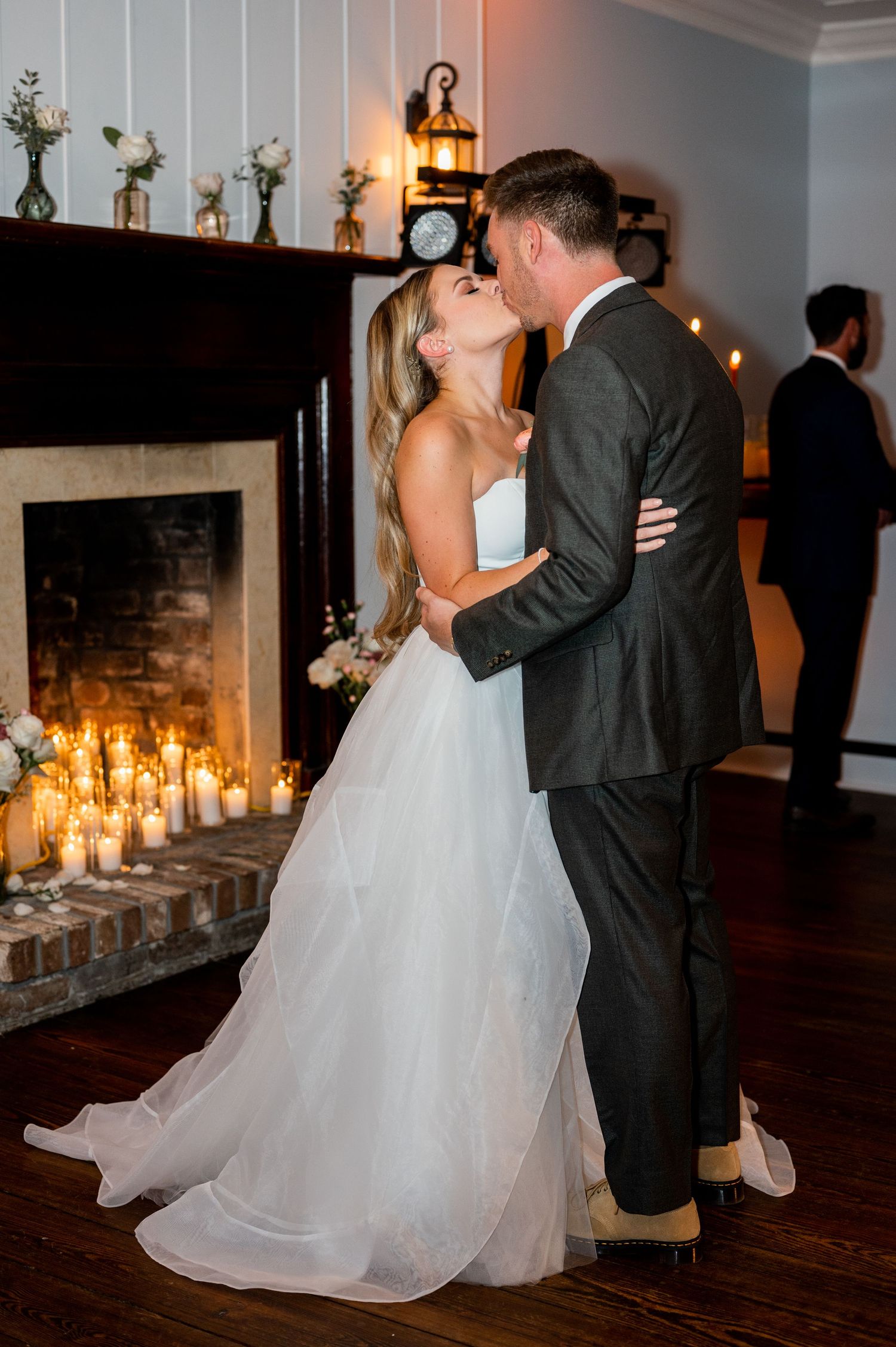 Romantic first dance with candlelit fireplace in the background at wedding reception.