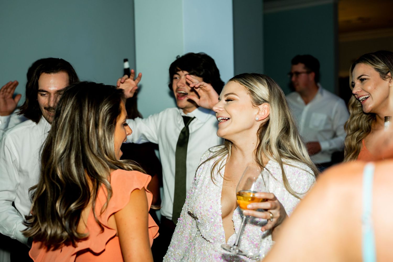 Wedding celebration showing guests dancing and mingling in an indoor venue.