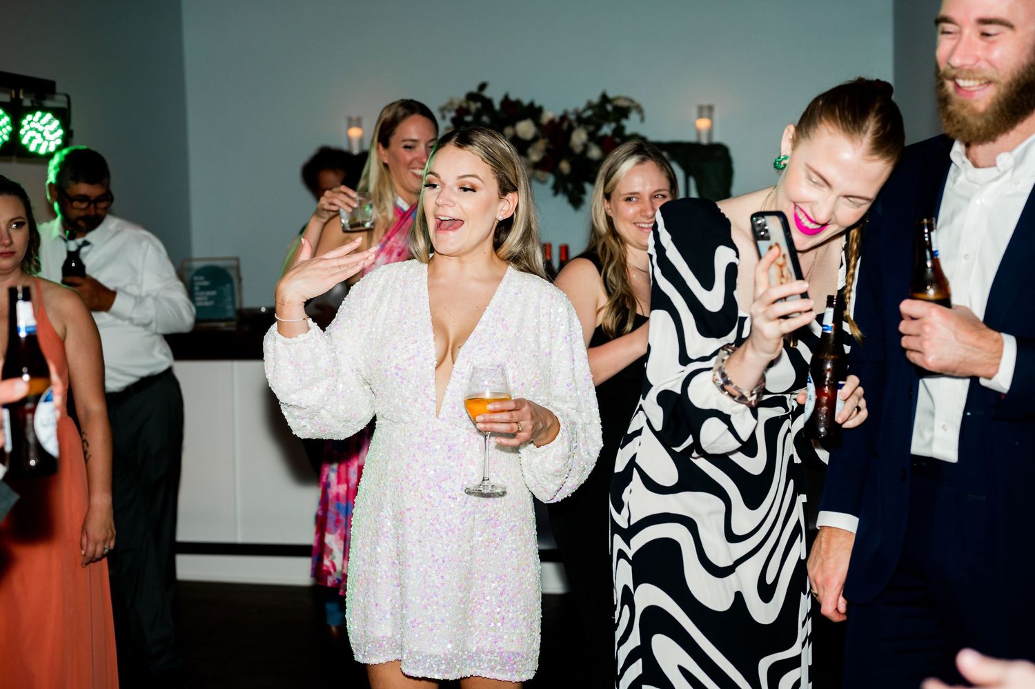Wedding guests socializing and dancing under decorative lighting at reception.