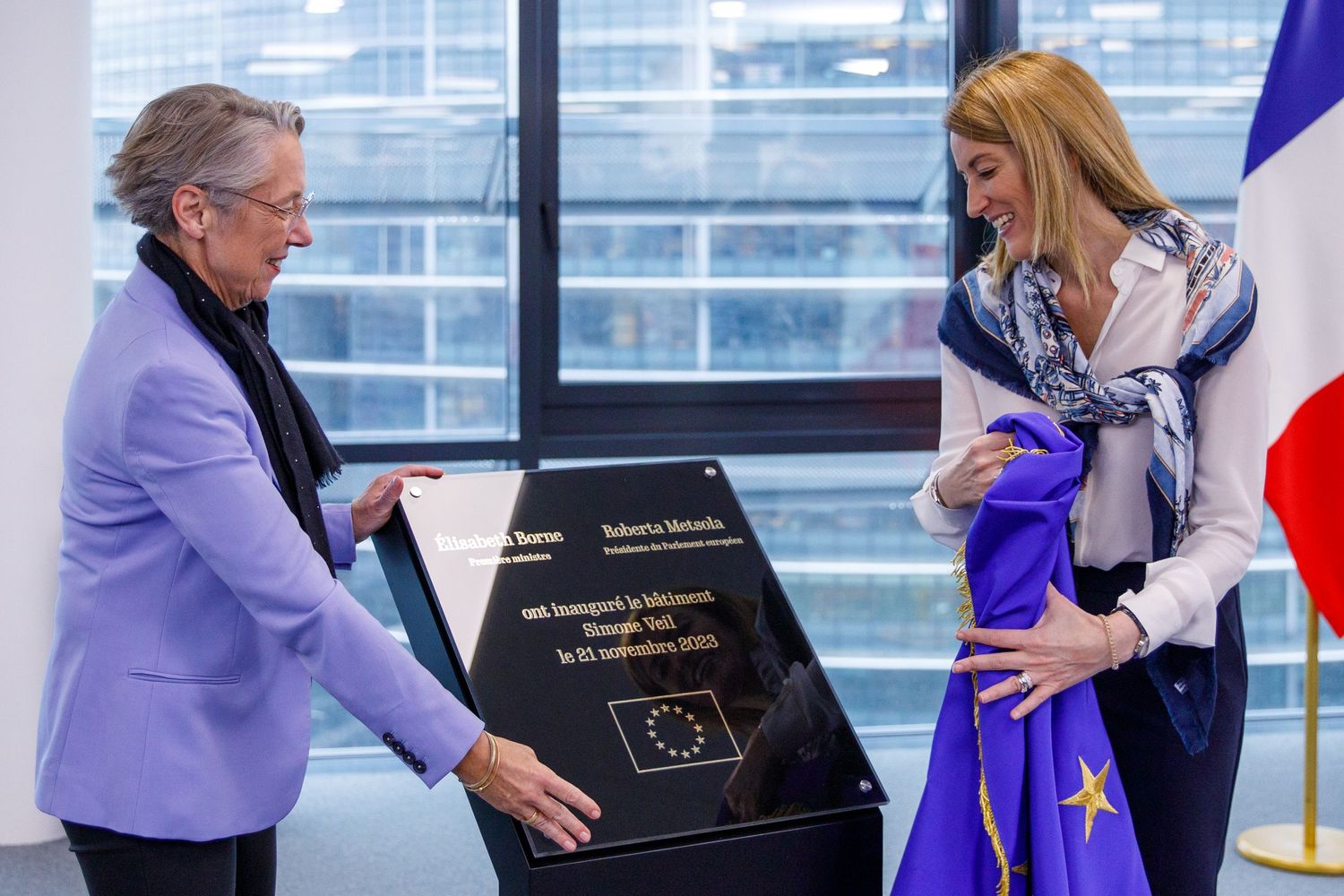 Officials unveiling a commemorative plaque with the EU flag displayed.