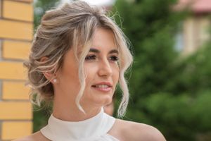 Side profile views of a styled updo hairstyle with loose curls against a brick wall.