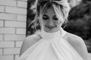 Portrait series featuring a white high-neck dress against a light brick wall background.