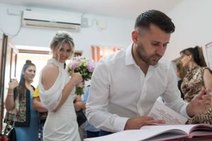 Group signing papers at a white table in a bright indoor space.