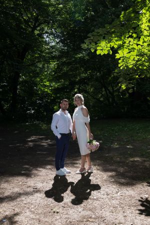Wedding couple walking together on sunlit garden path.