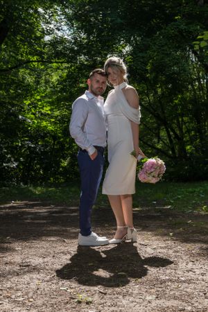 A couple shares an intimate moment in a sunlit wooded area during a photo session.